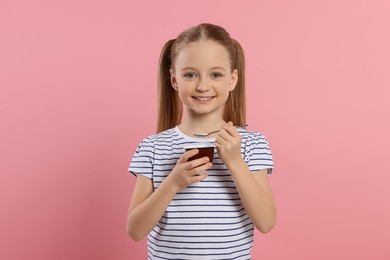 Photo of Cute little girl with tasty yogurt on pink background