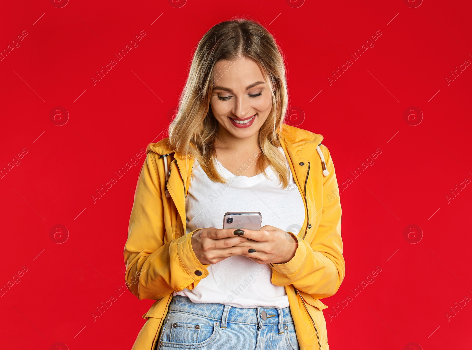 Photo of Beautiful woman using phone on red background