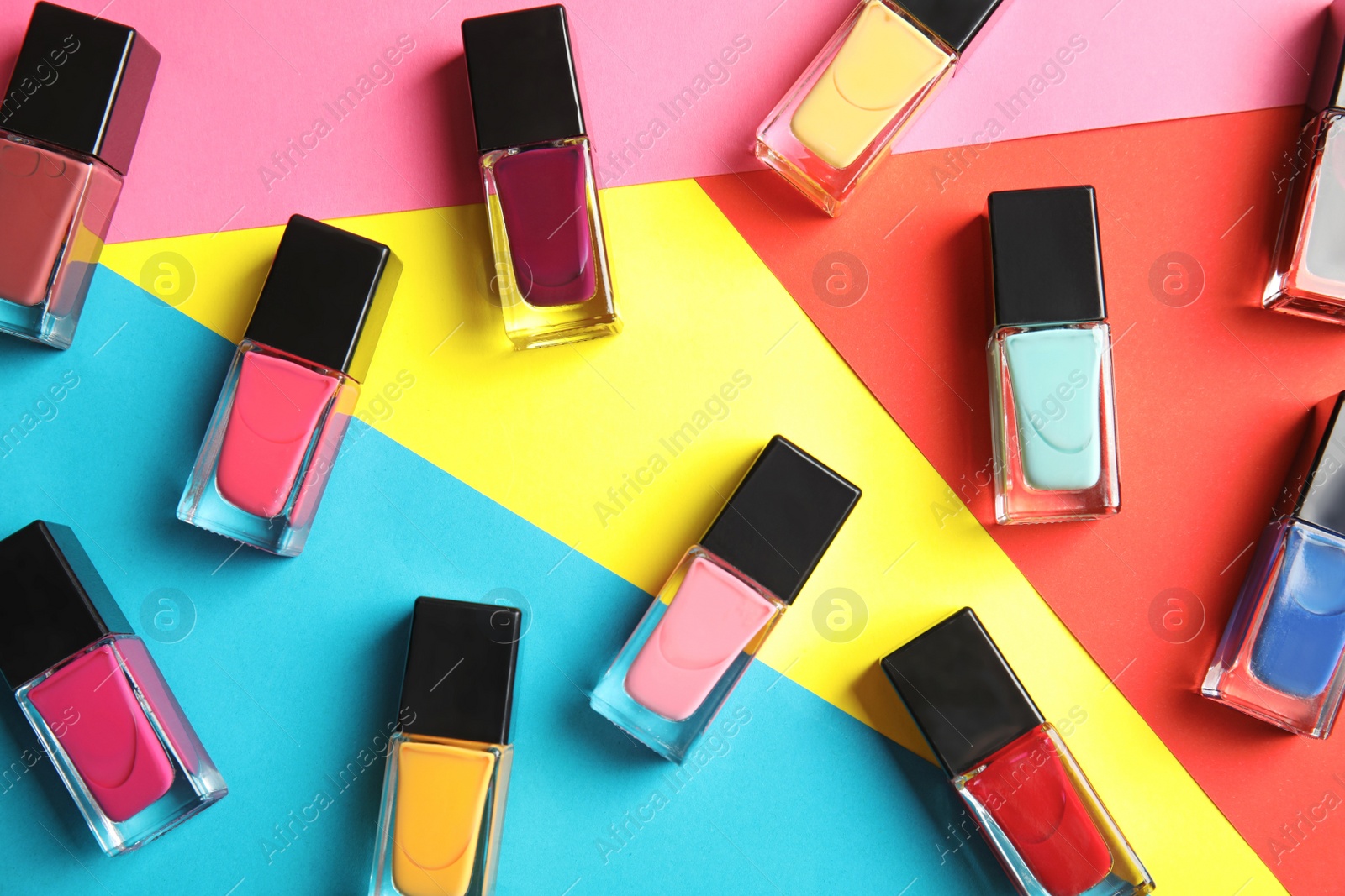 Photo of Bottles of nail polish on color background, top view