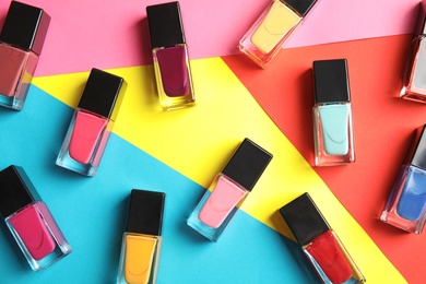 Bottles of nail polish on color background, top view