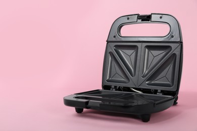 Open electric sandwich maker on pink background, space for text