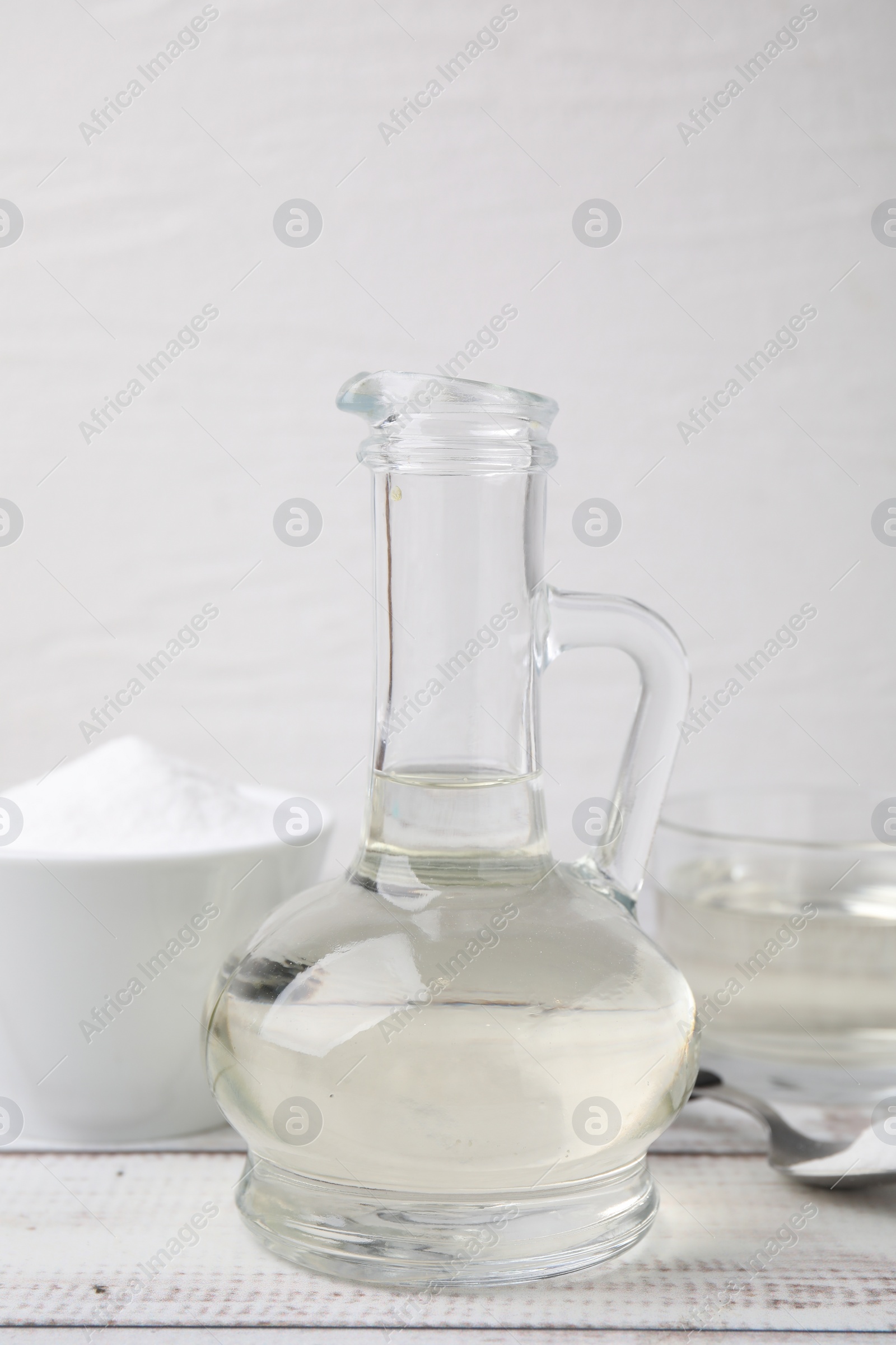 Photo of Vinegar and baking soda on white wooden table