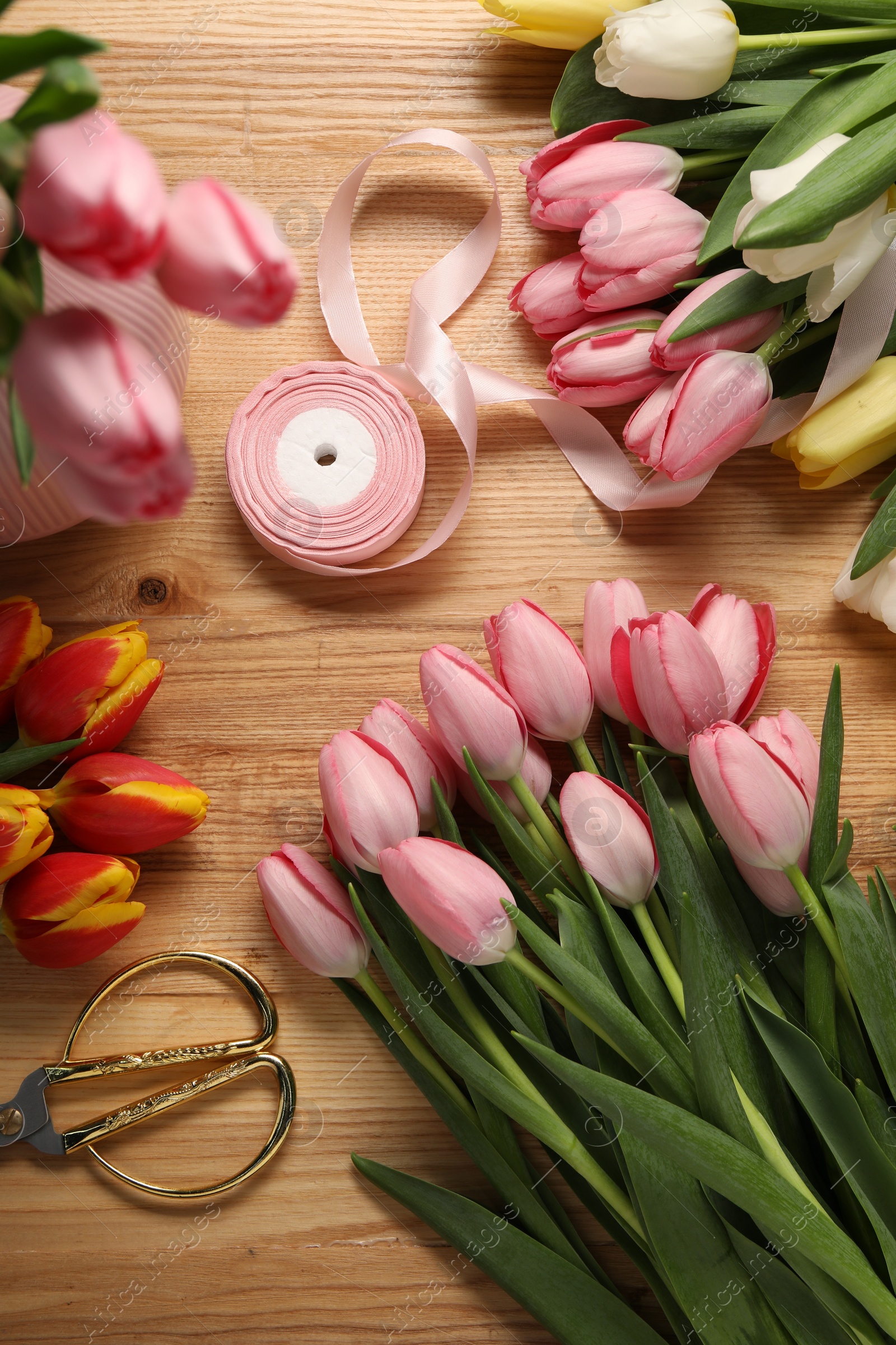 Photo of Making beautiful bouquet. Fresh tulips, ribbon and scissors on wooden table, flat lay