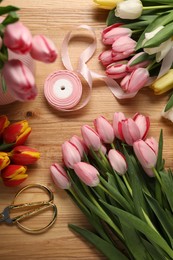 Photo of Making beautiful bouquet. Fresh tulips, ribbon and scissors on wooden table, flat lay