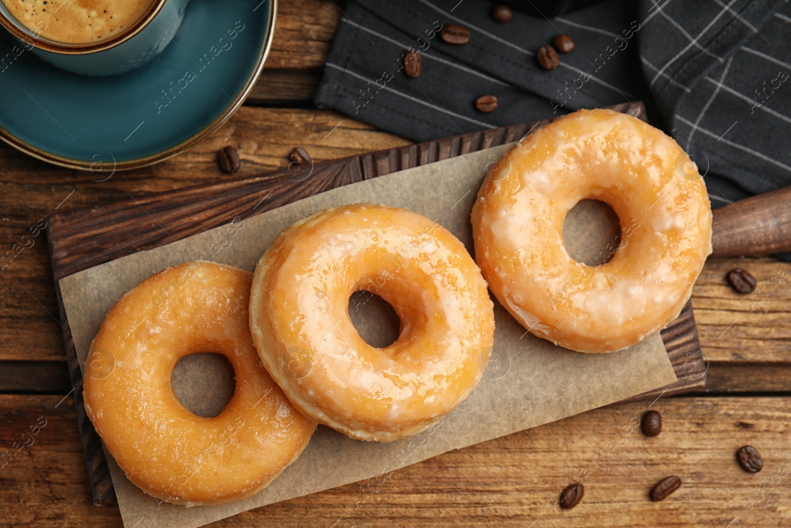 Photo of Delicious glazed donuts on wooden table, flat lay