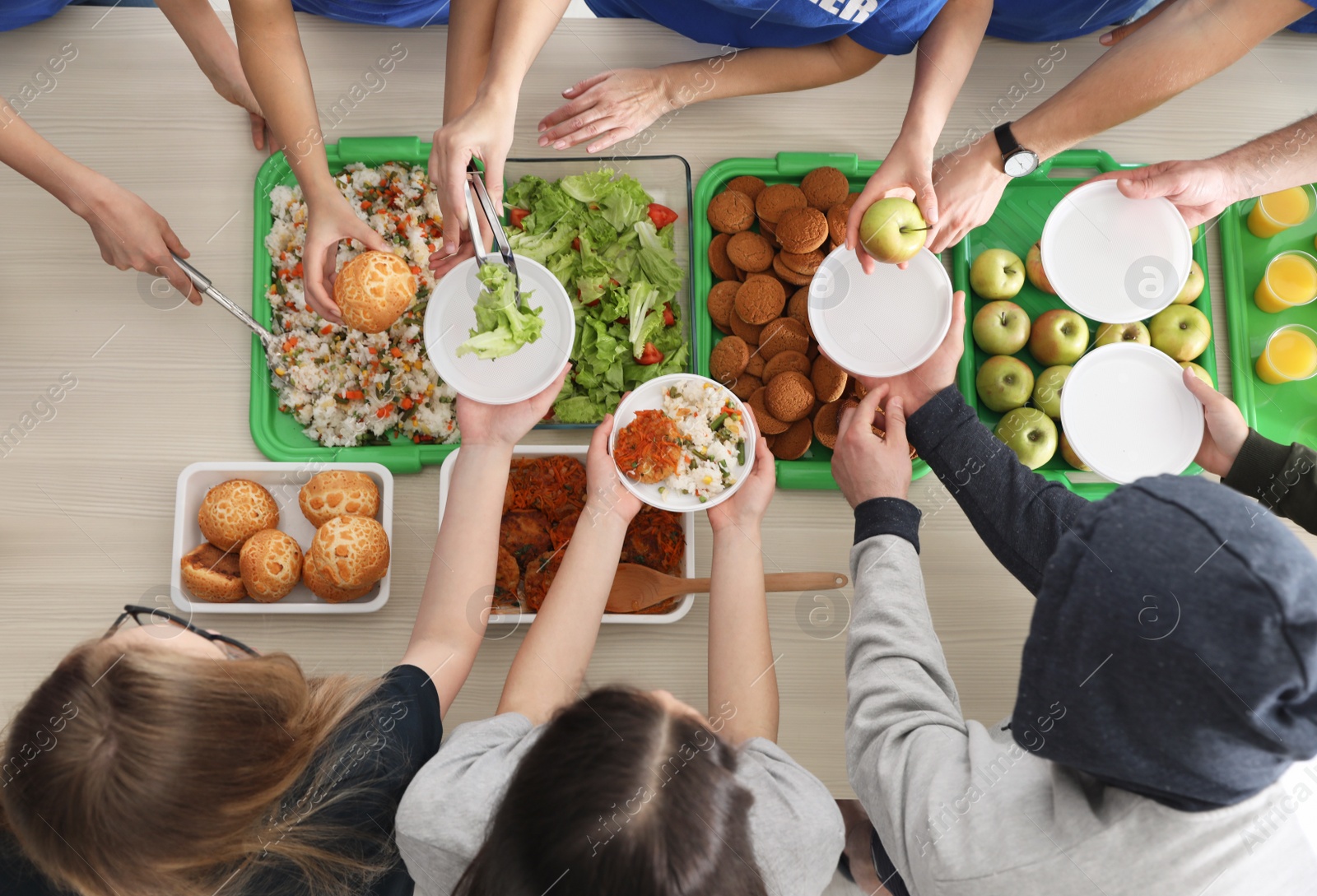 Photo of Volunteers serving food to poor people at table, top view