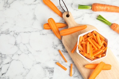 Photo of Bowl with cut ripe carrot on wooden board, top view