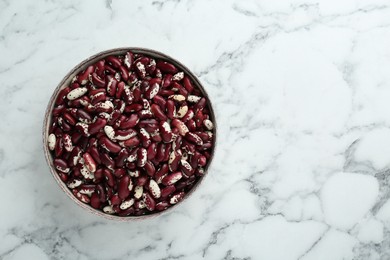 Photo of Bowl with dry kidney beans on white marble table, top view. Space for text