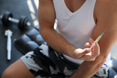 Photo of Sportsman injecting himself in gym, closeup. Doping concept