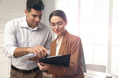 Businesswoman helping intern with work in office