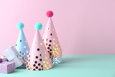 Party hats and gift boxes on color background, space for text