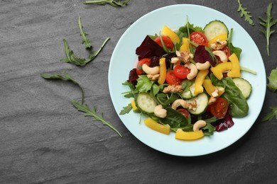 Photo of Tasty fresh vegetarian salad on black table, top view. Space for text