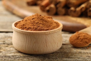 Photo of Bowl of cinnamon powder on wooden table, closeup