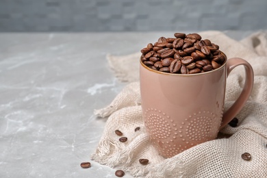 Ceramic cup with coffee beans on table