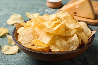 Photo of Delicious crispy potato chips in bowl on table, closeup