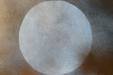 Photo of Light grey textured background covered with golden spray paint and circle left undyed