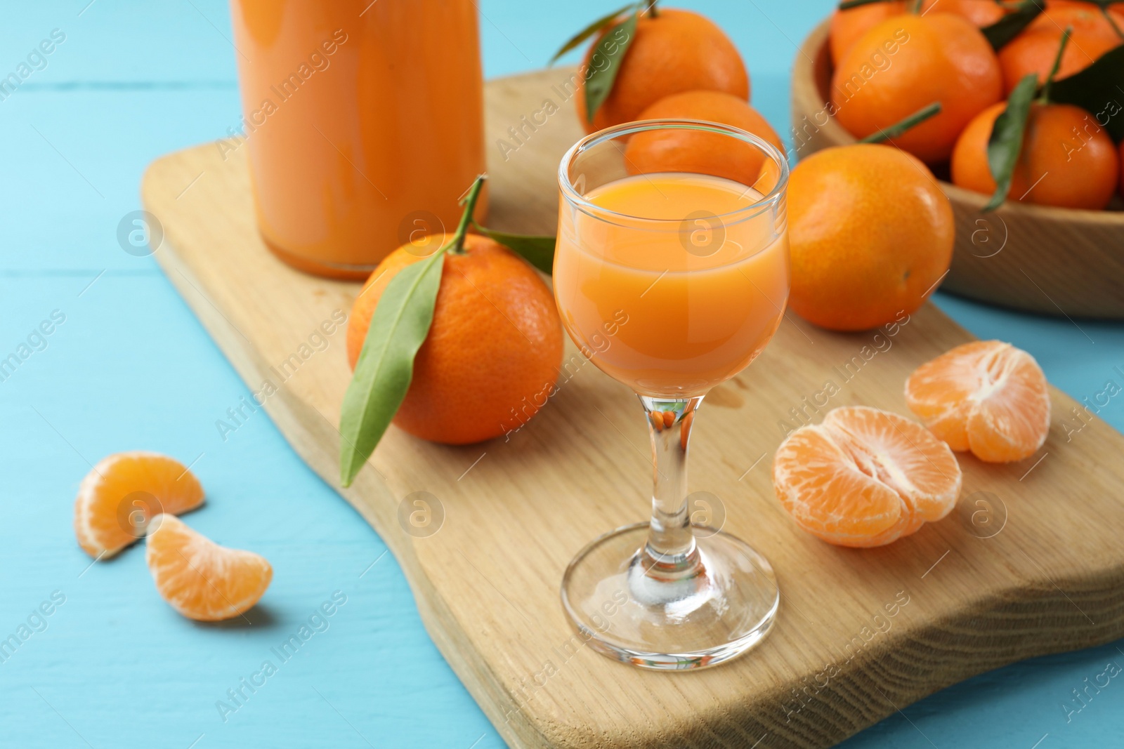 Photo of Delicious tangerine liqueur and fresh fruits on light blue wooden table