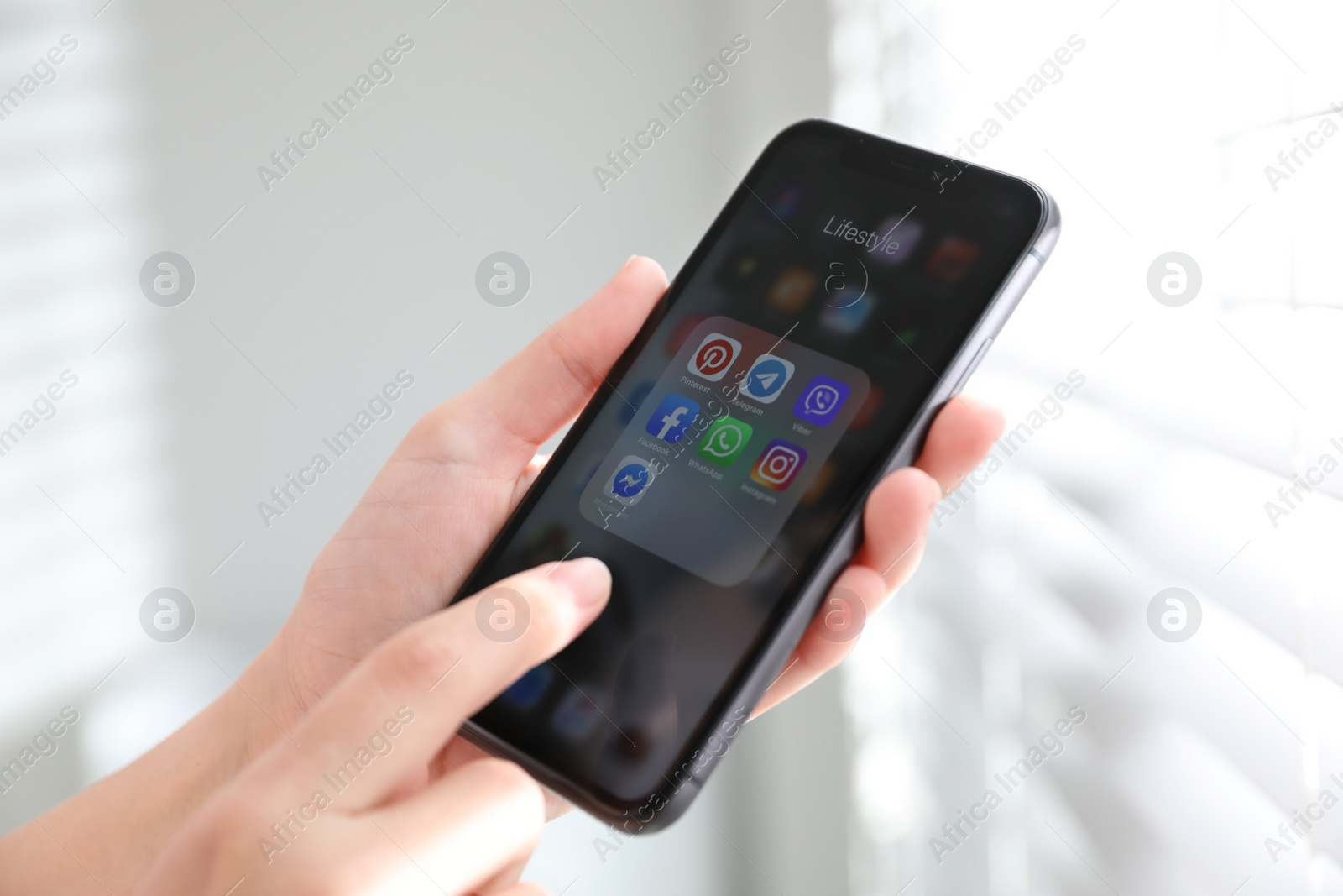 Photo of MYKOLAIV, UKRAINE - MARCH 16, 2020: Woman holding iPhone 11 with social media icons on screen indoors, closeup