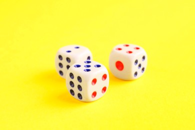 Photo of Three white game dices on yellow background, closeup