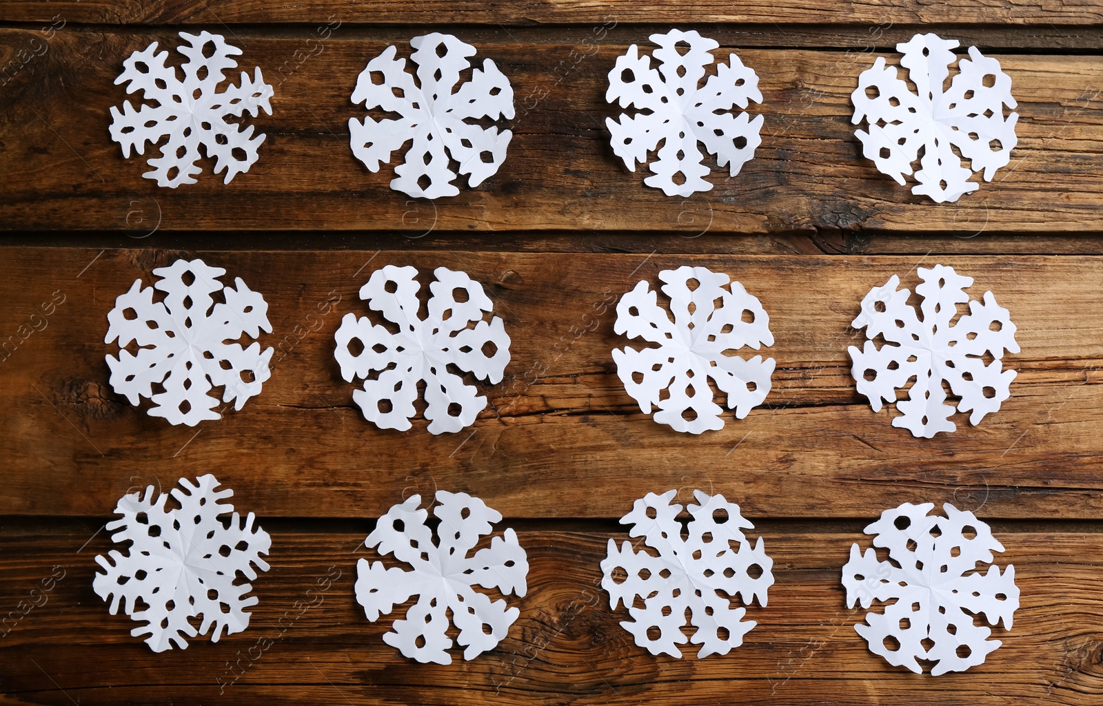 Photo of Many paper snowflakes on wooden background, flat lay