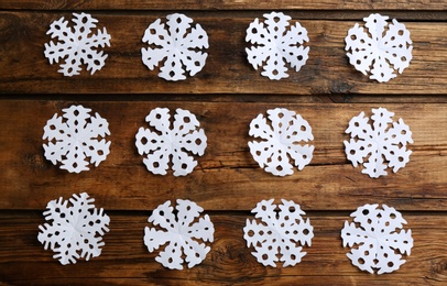 Many paper snowflakes on wooden background, flat lay