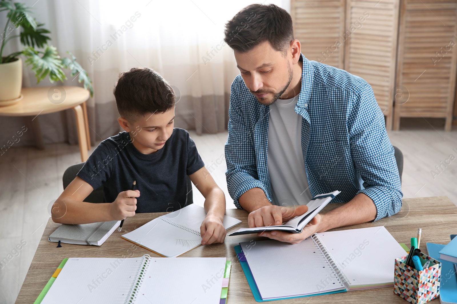 Photo of Dad helping his son with homework in room