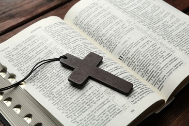 Photo of MYKOLAIV, UKRAINE - DECEMBER 21, 2021: Wooden cross and Bible on table, closeup. Text in russian