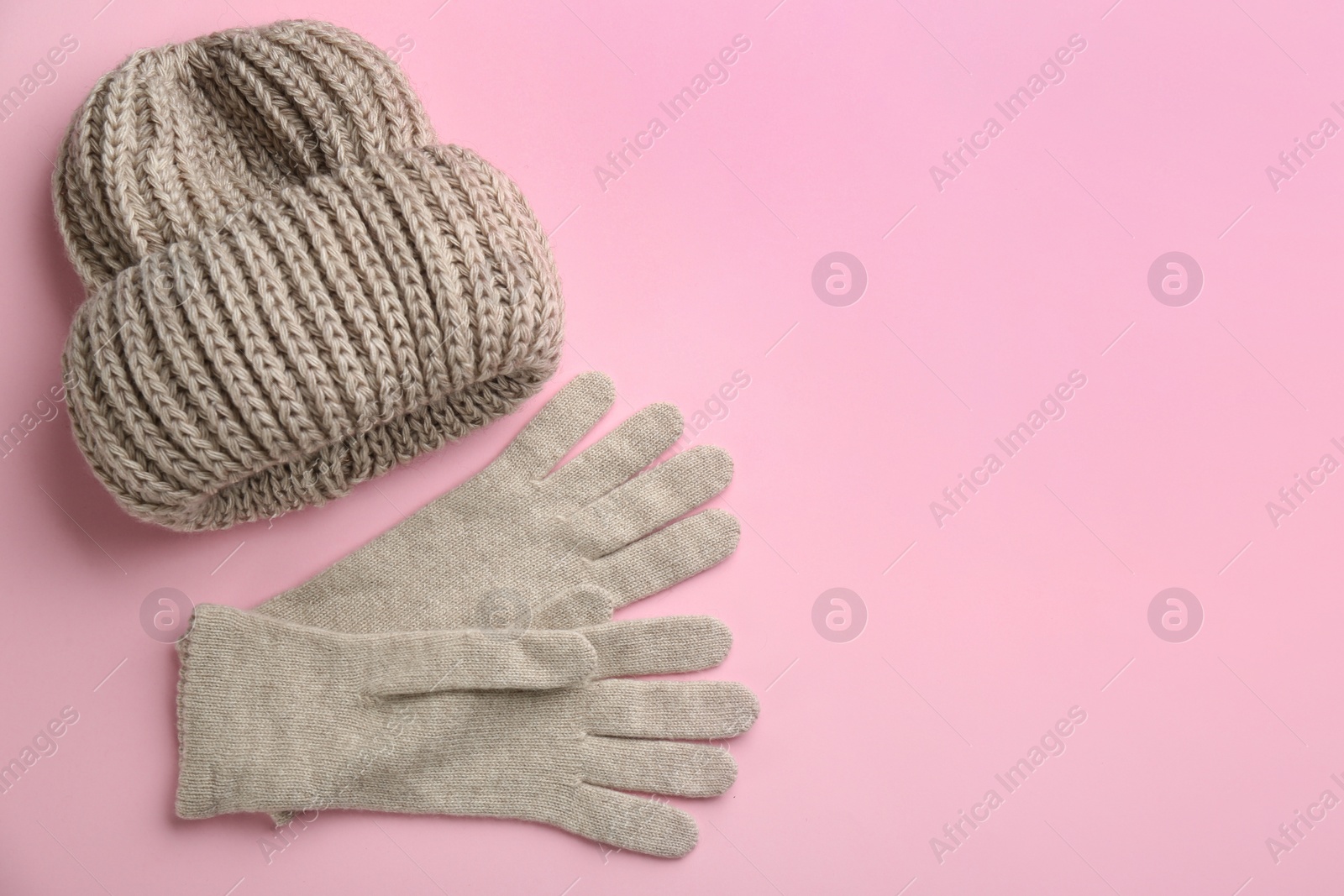 Photo of Woolen gloves and hat on pink background, flat lay. Space for text