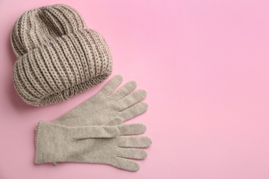 Woolen gloves and hat on pink background, flat lay. Space for text