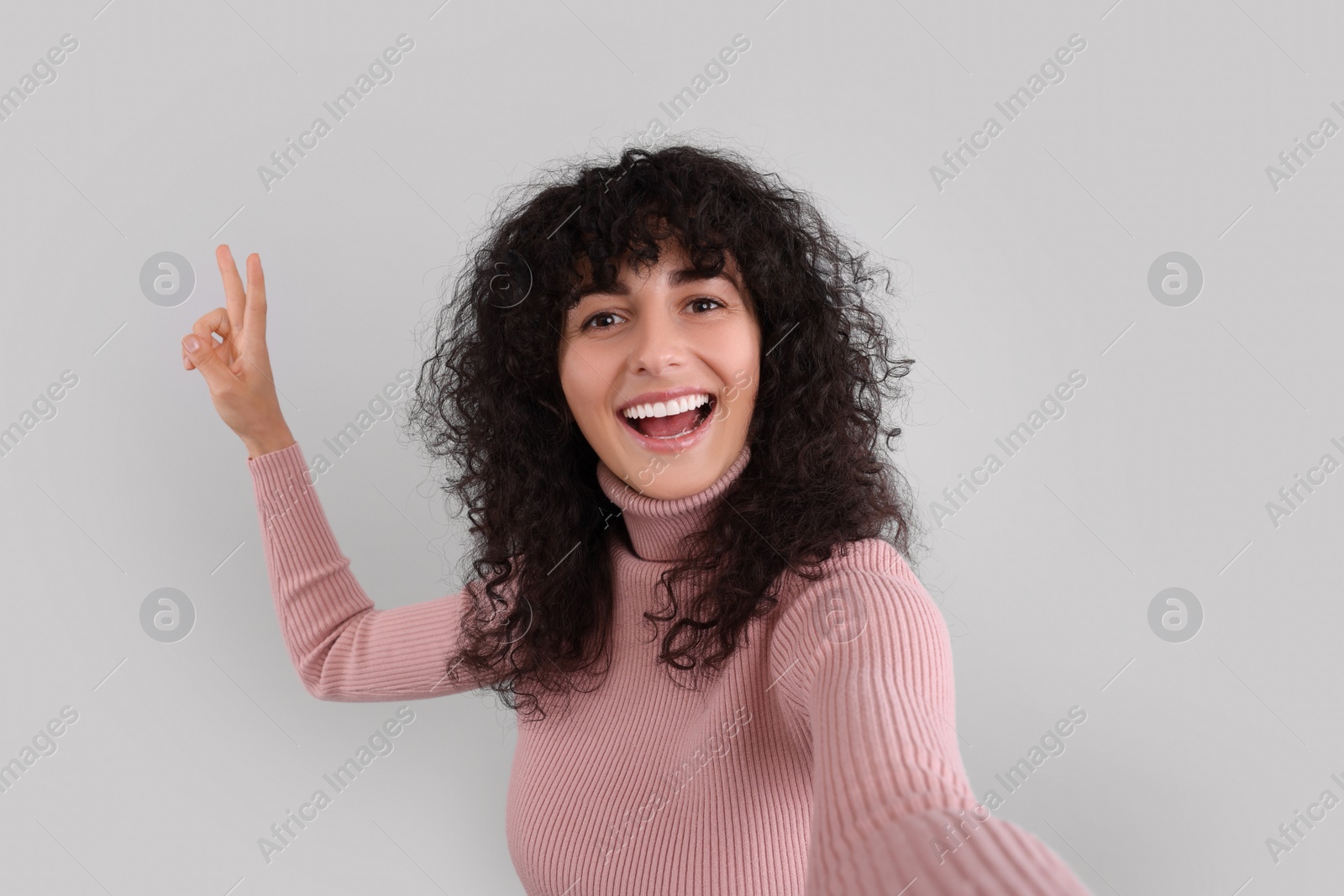 Photo of Beautiful young woman taking selfie on light grey background