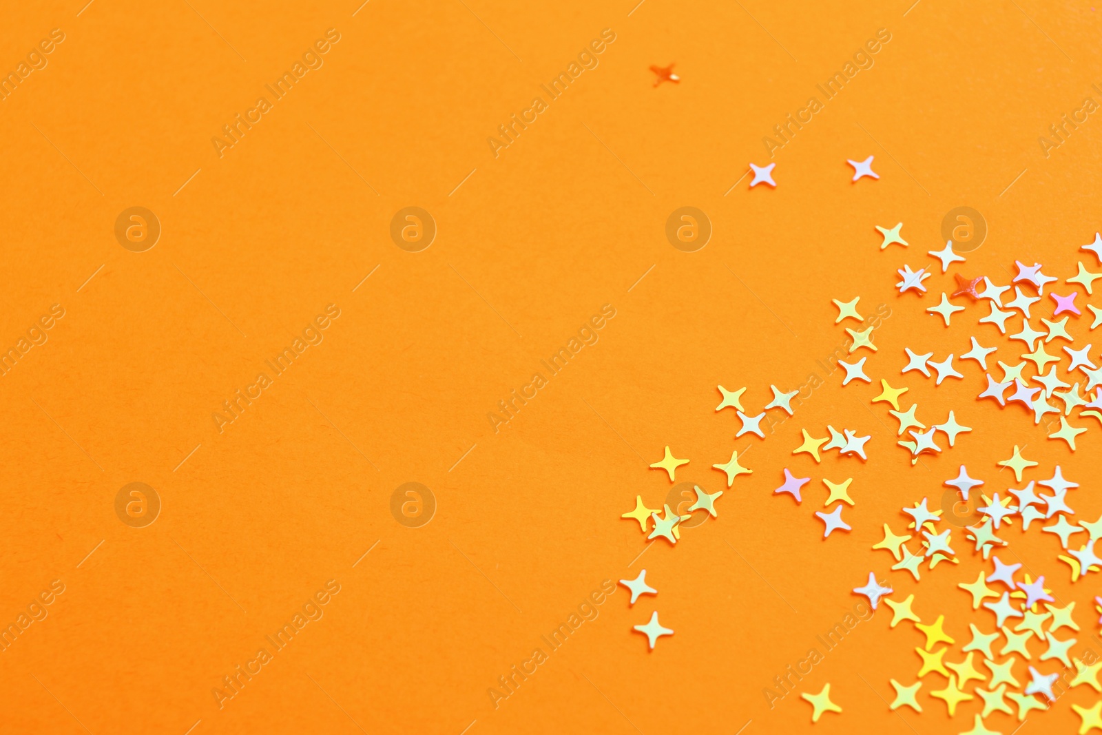 Photo of Shiny bright glitter on pale orange background. Space for text