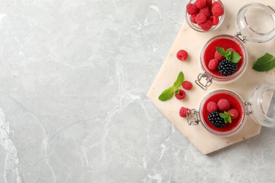 Photo of Delicious panna cotta with fruit coulis and fresh berries on light grey table, top view. Space for text