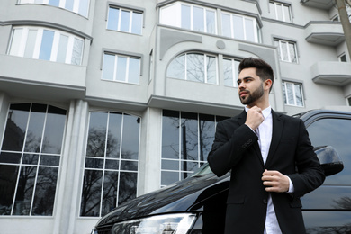 Photo of Handsome young man near modern car outdoors, low angle view