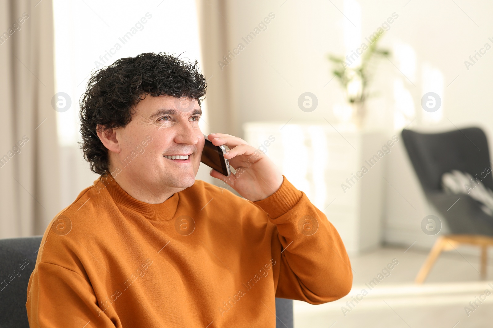 Photo of Mature man talking on mobile phone indoors. Space for text