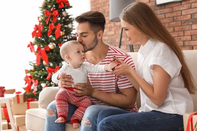 Happy couple with baby celebrating Christmas together at home