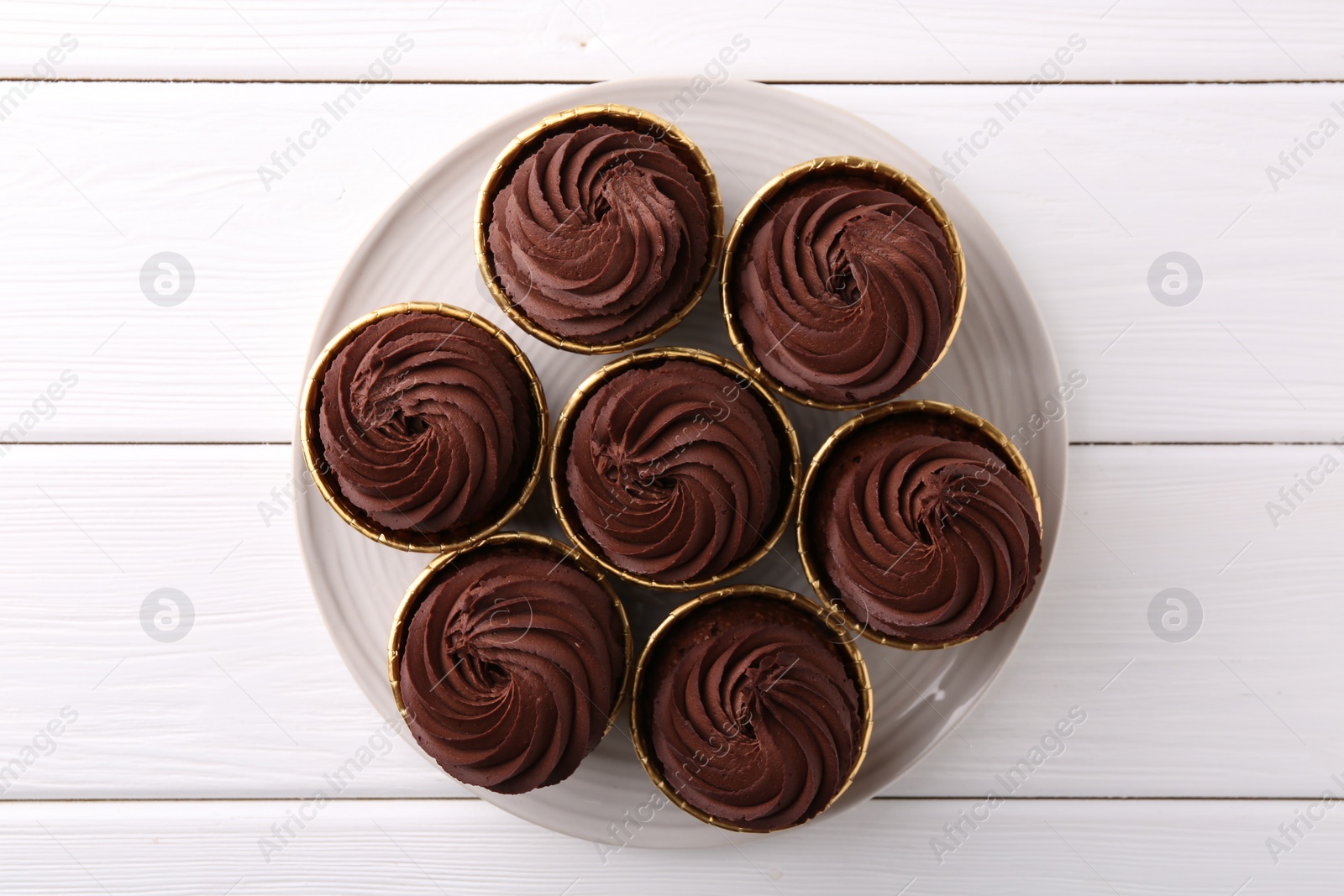 Photo of Delicious chocolate cupcake on white wooden table, top view