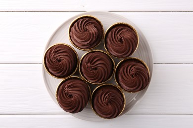 Delicious chocolate cupcake on white wooden table, top view