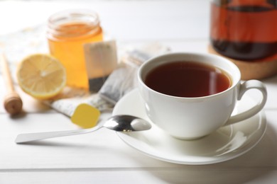 Tea bags, sugar and lemon near cup of hot drink on white wooden table, closeup