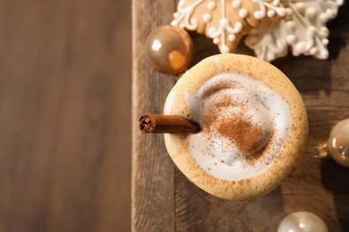 Tasty eggnog with cinnamon, cookies and Christmas baubles on wooden table, flat lay. Space for text