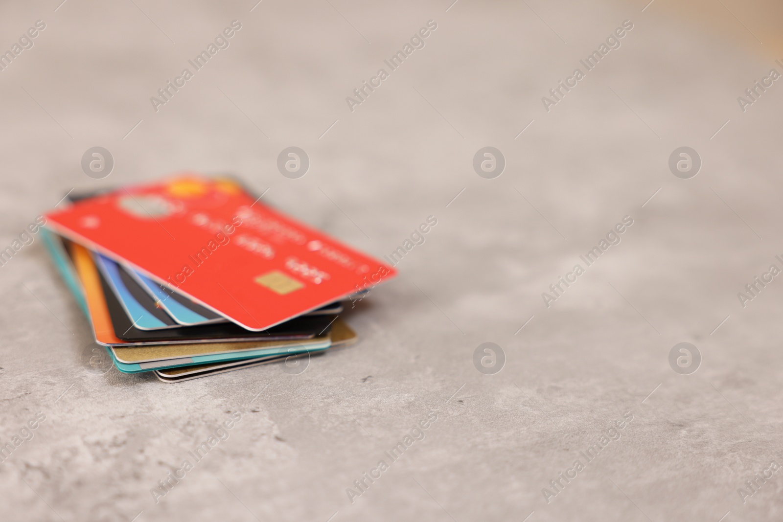 Photo of Pile of different credit cards on grey table, closeup. Space for text