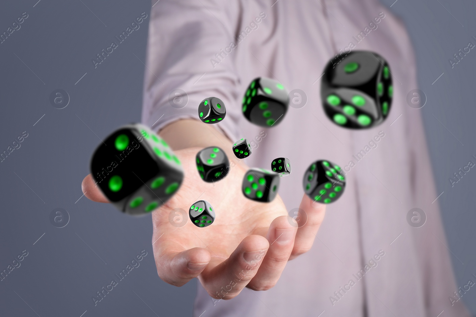 Image of Man throwing black dice on grey background, closeup