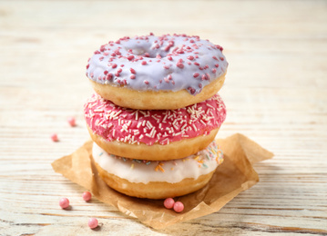 Photo of Delicious glazed donuts on white wooden table