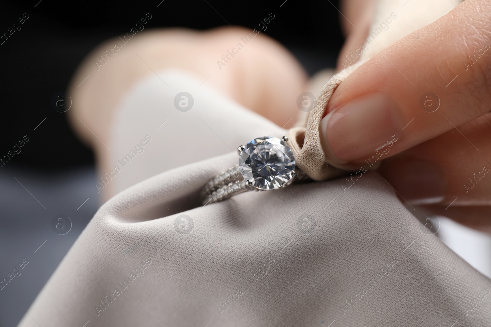 Photo of Jeweler cleaning diamond ring with microfiber cloth, closeup