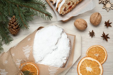 Photo of Wrapped Christmas Stollen with decoration on wooden table, flat lay