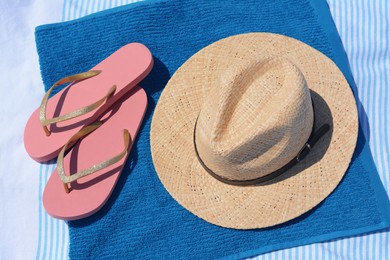 Photo of Blue towel, flip flops and straw hat on blanket, above view