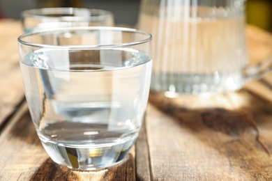 Glass of water on wooden table, closeup. Refreshing drink