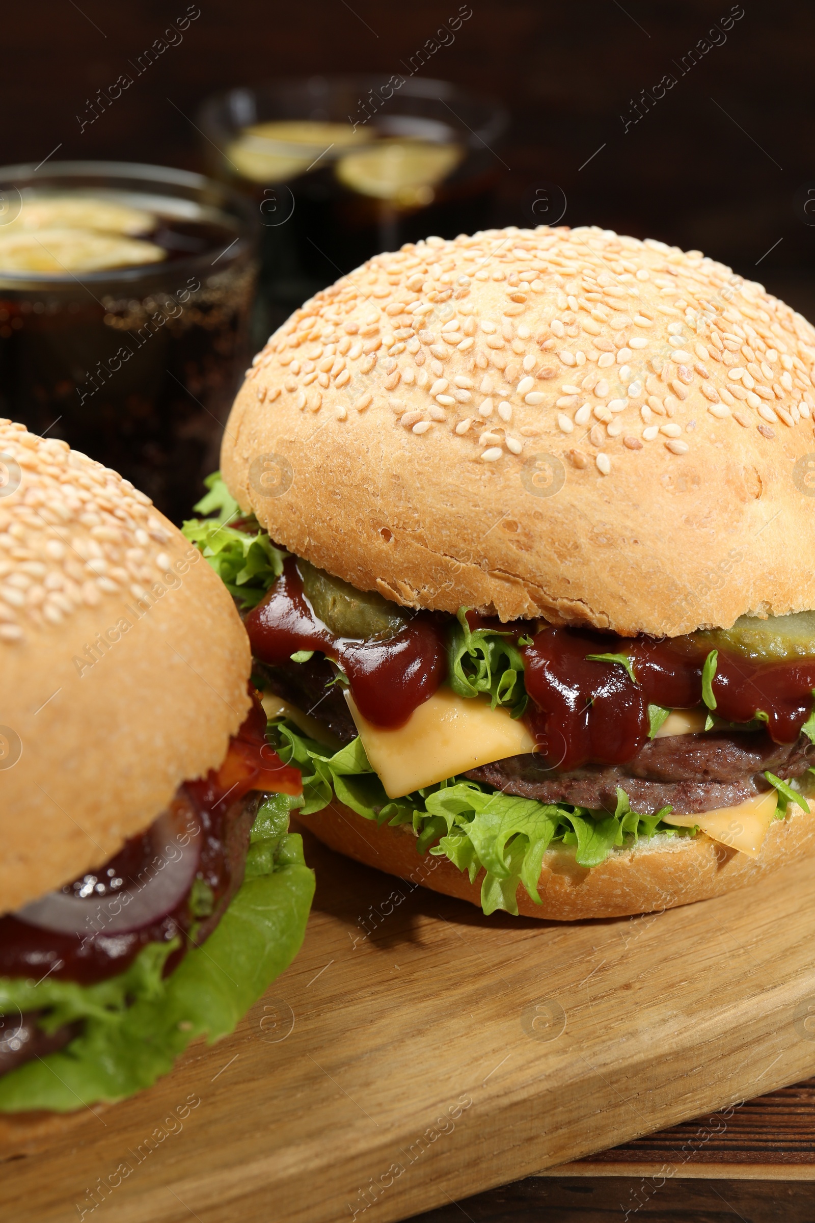 Photo of Board with delicious cheeseburgers on table, closeup