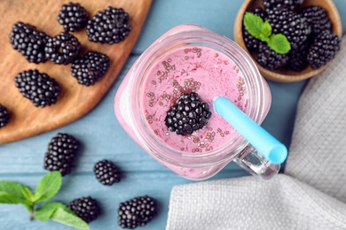 Flat lay composition with delicious blackberry smoothie on blue wooden background