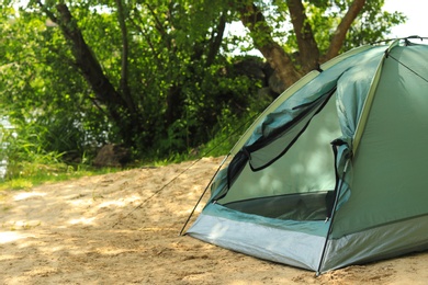 Modern camping tent near trees in wilderness