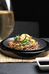 Photo of Stir-fry. Tasty noodles with meat and vegetables served on dark textured table